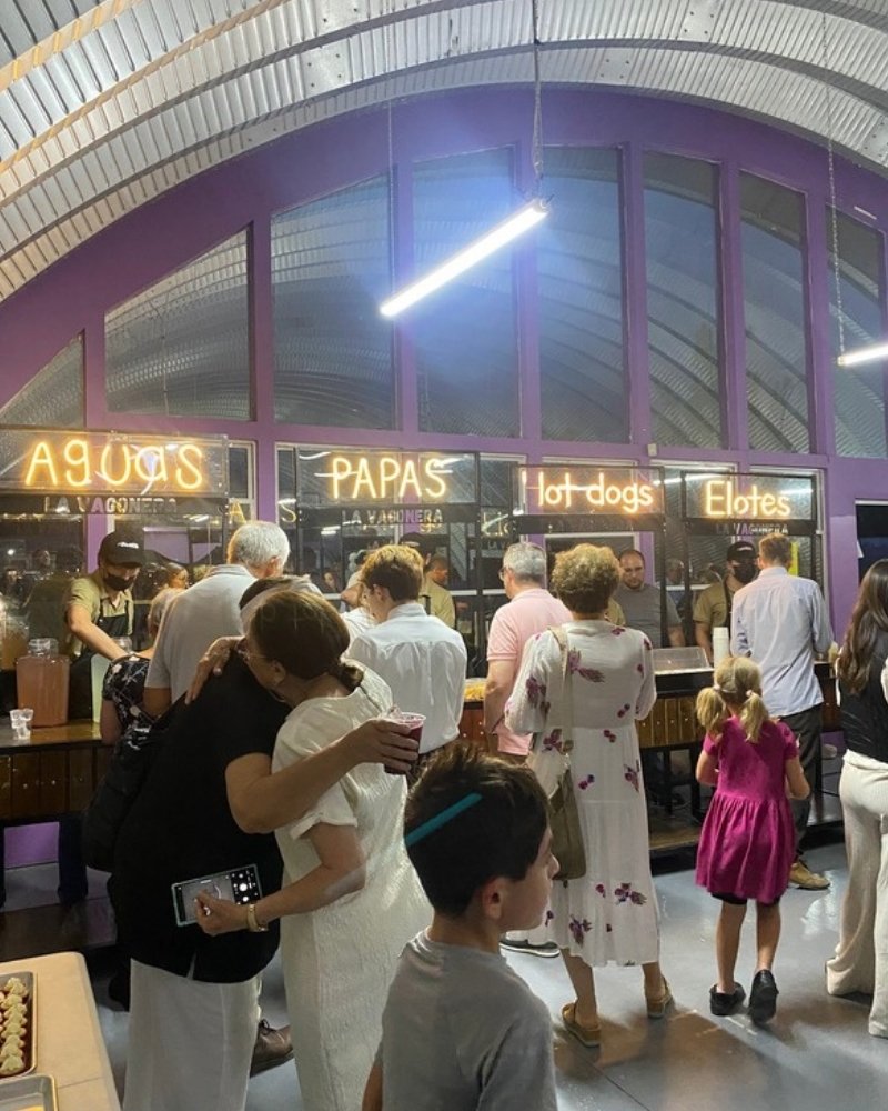 Invitados formados en los carritos de aguas, papas, hot dogs y elotes de La Vagonera