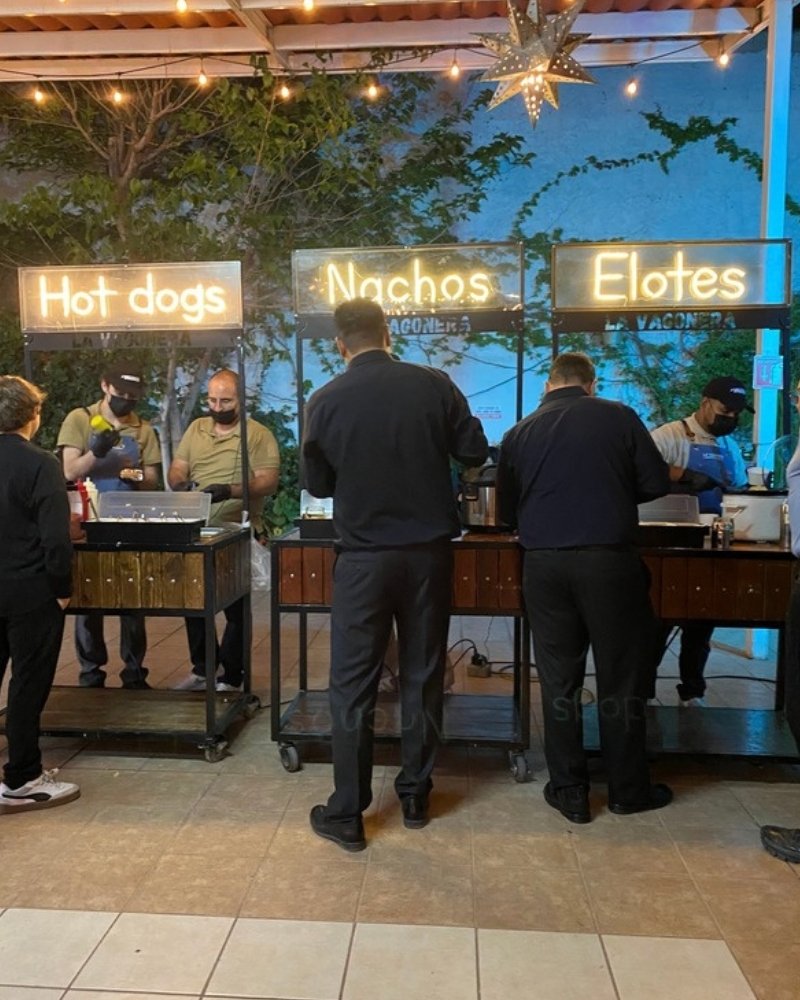Invitados en los carritos de hot dogs, nachos y elotes de La Vagonera en una terraza