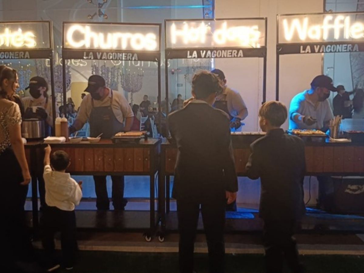 Carritos de La Vagonera en un evento de noche: elotes, churros, hot dogs y waffles